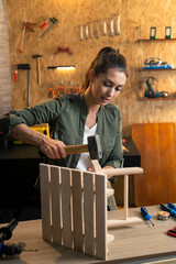 Woman carpenter tightening up a wooden chair