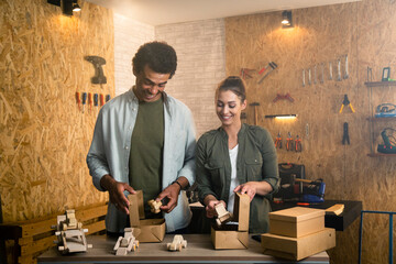 Two people in a carpentry workshop packing and shipping wooden products in boxes.
