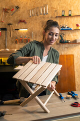 Woman carpenter tightening up a wooden chair