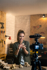 Woman in a carpentry workshop being filmed with a camera for a blog.