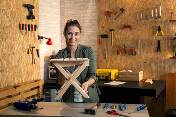 Woman In carpenter workshop showing wooden chair