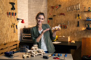 Portrait of woman in carpenter workshop showing wooden toys