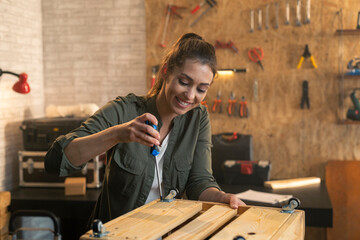 Portrait of woman in carpenter workshop working with screwdriver