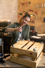 Portrait of woman in carpenter workshop working with screwdriver