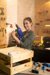 Portrait of woman carpenter with drill in workshop