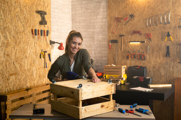 Portrait of woman carpenter with drill in workshop