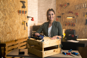 Portrait of woman carpenter with drill in workshop