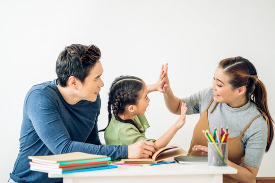 Portrait enjoy happy love asian family father and mother with little asian girl learn and study on table.Mom and dad with asian girl writing with book make homework in homeschool at home.Education