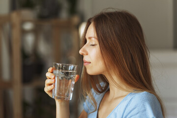 Portrait of young woman drinking pure glass of water, close up. 