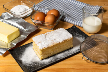 A piece of layered white cream cake with powdered sugar and ingredients, dessert for the celebration. White Cream pie