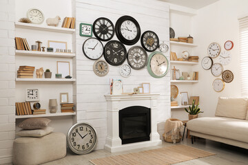 Stylish room interior with comfortable sofa, fireplace and collection of wall clocks