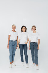 Obraz premium Full length of smiling women in white t-shirts standing on grey background.