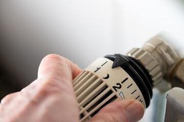 Close-up of hand turning thermostat down. Turn heating off. Gas price. Savings. High quality photo