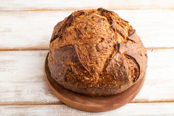 Fresh homemade golden grain bread with wheat and rye on white, side view, close up.