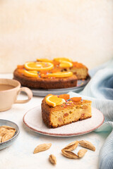 Orange cake with almonds and a cup of coffee on a white concrete background. Top view, selective focus.