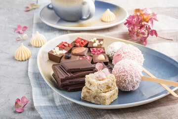 A pieces of homemade chocolate with coconut candies on a blue and brown textile. side view, selective focus.