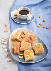traditional arabic sweets and a cup of coffee on a gray concrete background. side view, close up.