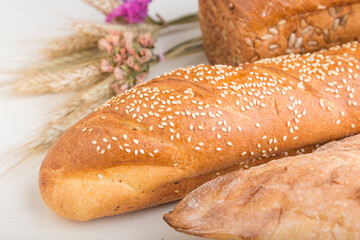 Different kinds of fresh baked bread on a white wooden background. side view.