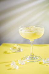 fresh banana and coconut tropical cocktail in a glass over yellow background