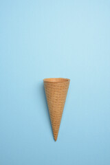 Cono para helados vacío sobre fondo azul, flat lay