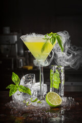 Cocktail drink with mint, lime and ice cubes on black background