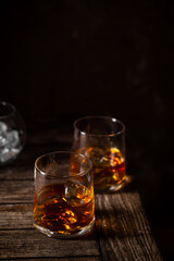 Two glasses of the whiskey with ice isolated on a dark background