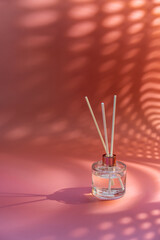 Aroma reed diffuser, home fragrance bottle with rattan sticks and smell of freshness on pink...