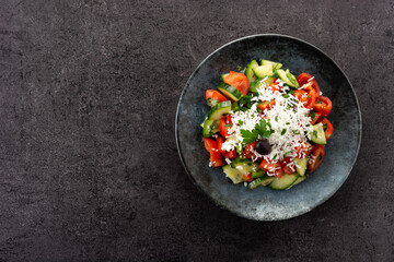 Traditional Bulgarian shopska salad with tomato,cucumber and bulgarian sirene cheese on black background.Top view. Copy space
