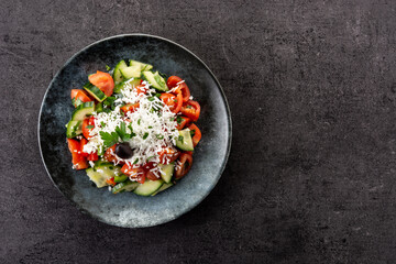 Traditional Bulgarian shopska salad with tomato,cucumber and bulgarian sirene cheese on black background.Top view. Copy space - obrazy, fototapety, plakaty
