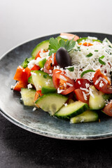 Traditional Bulgarian shopska salad with tomato,cucumber and bulgarian sirene cheese on black background