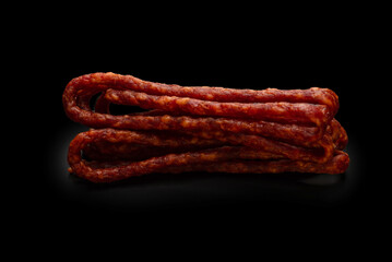 Cabanossi, dry sausage isolated on black background.