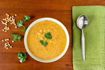 Yellow split peas lentil soup, garnished with corrinader leaves, in a bowl with a spoon and napkin...
