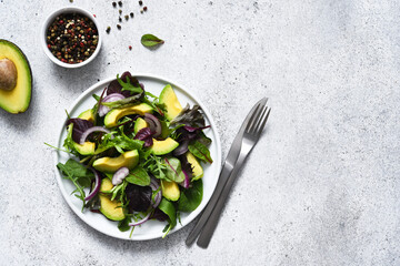 Mix salad with avocado and sauce on a concrete background.