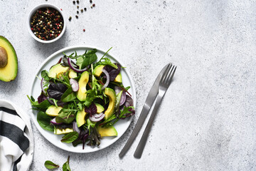 Mix salad with avocado and sauce on a concrete background.