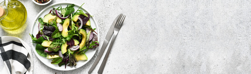 Mix salad with avocado and sauce on a concrete background.