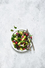 Obraz na płótnie Canvas Mix salad with arugula, avocado and raspberries on a stone concrete background. View from above