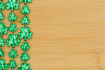 Green shamrocks on light brown grained wood background
