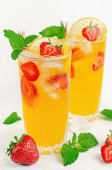 Orange summer cocktail with strawberries, lemon and ice on white background.