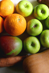 Green apples, oranges, mango, butternut squash, onion and sweet potato on the table. Flat lay.