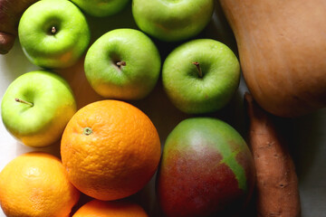 Green apples, oranges, mango, butternut squash, onion and sweet potato on the table. Flat lay.