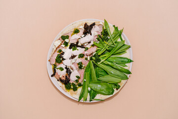 Italian Piadina with roast beef, sun-dried tomatoes, wild garlic, pesto, mozzarella and bechamel sauce. Beige background. Top view. Copy space