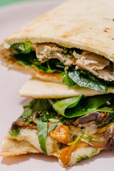 Italian Piadina with oyster mushrooms, spinach, pesto, mozzarella, bechamel, gorgonzola cheese, green onions. Green background. Close up