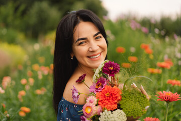 A Young woman walks with a bouquet of flowers in a floristic flower farm. Woman florist. Floristics concepts.