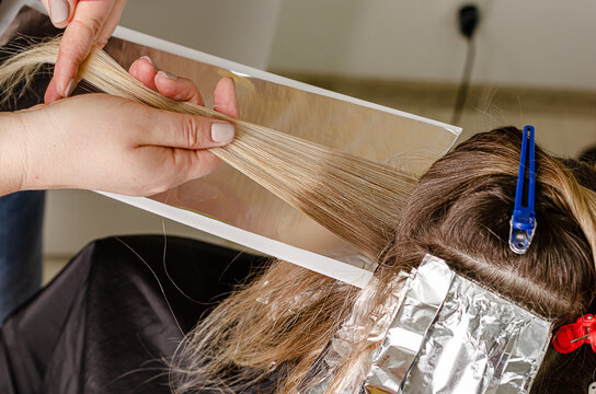 Process of applying bleaching powder on clients hair and wrapping into the foil. AirTouch technique