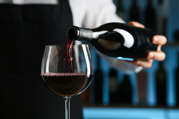 Bartender pouring wine into glass in restaurant, closeup