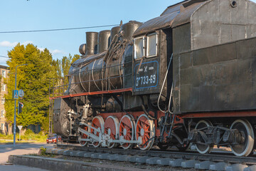 Fototapeta na wymiar Old locomotive -Em-733-69. Monument at the railway station in the city of Krivoy Rog in Ukraine. summer sunny day