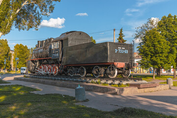 Fototapeta na wymiar Old locomotive -Em-733-69. Monument at the railway station in the city of Krivoy Rog in Ukraine. summer sunny day