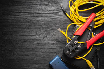 Computer network cable crimper, switch and cable on the black flat lay background with copy space.