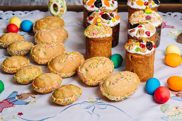 Retro styled easter cookies of egg form, traditional ukrainian easter Kulich cake, and Easter eggs on a wooden desk on embroidered handmade towel