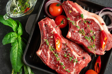 Fresh veal bone steaks on grill pan with spices and herbs. Cooking concept. Flat lay, top view